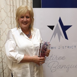 Leslie Hicks smiles a for picture with her vase at the 2023 Retiree Banquet